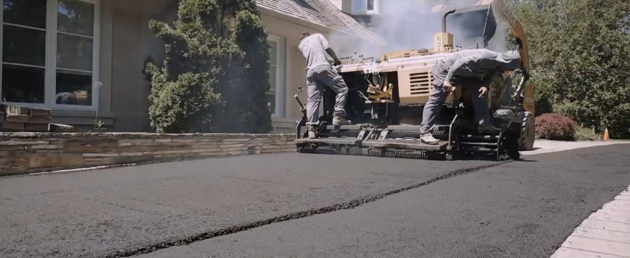 Asphalt paver and crew on a residential driveway